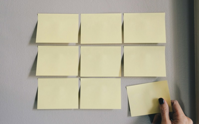 Nine sticky notes stuck to the wall in a grid