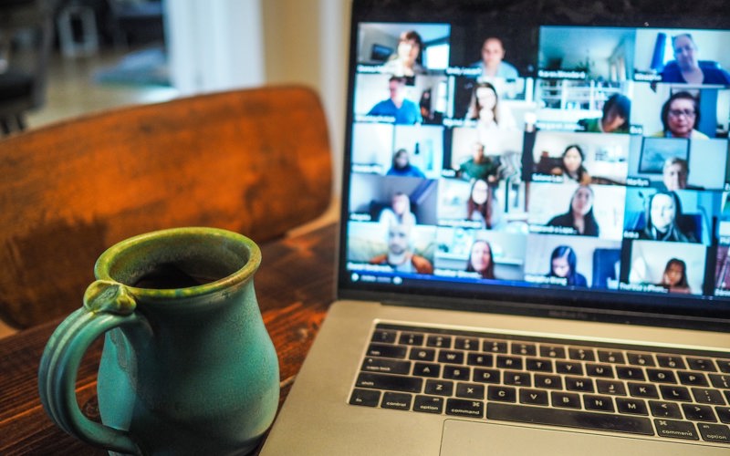 China mug in front of a laptop screen showing an online meeting