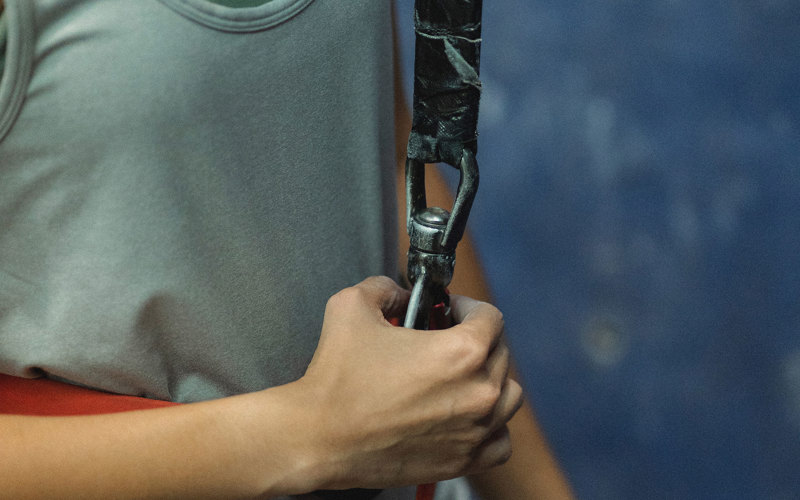 A hand holds the connection on a climbing rope to a harness.