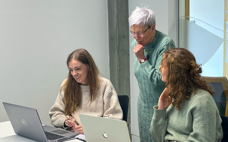 Three people looking at a laptop