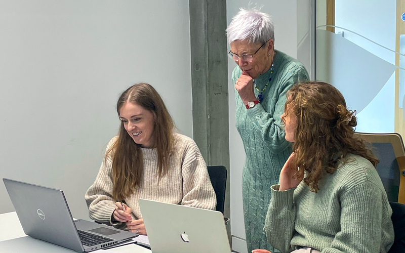 Three people looking at a laptop