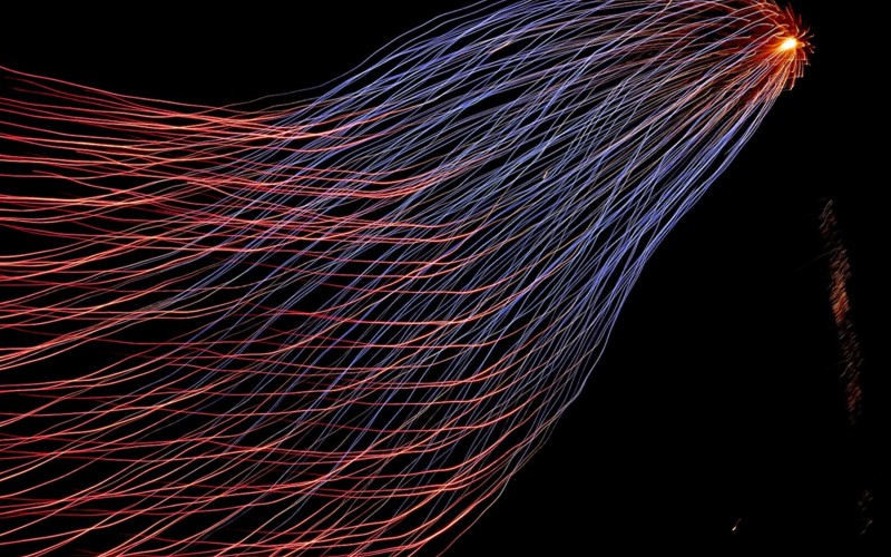 Timelapse photo showing different coloured intertwined light trails 