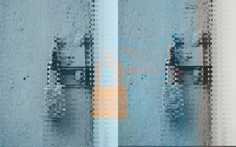 An old padlock attached to blue wood door